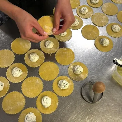Des mains qui garnissent des raviolis frais, un à un, sur le plan de travail