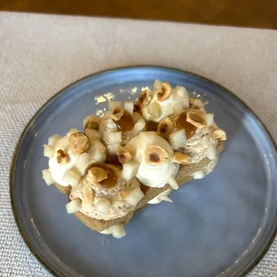 Tartine grillée, noisettes torréfiées et oignons doux, servie à l'assiette